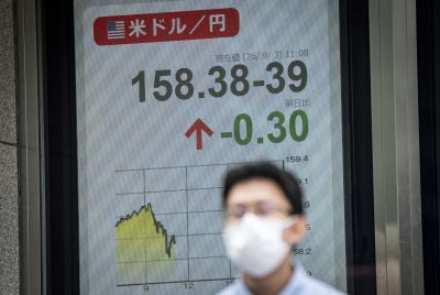 一名男子走过一块显示着报价的电子显示屏。